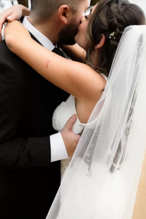 Close-up of the couple sharing a kiss, the bride’s veil and braided hair softly framing the moment at Marimurtra Botanical Garden.
