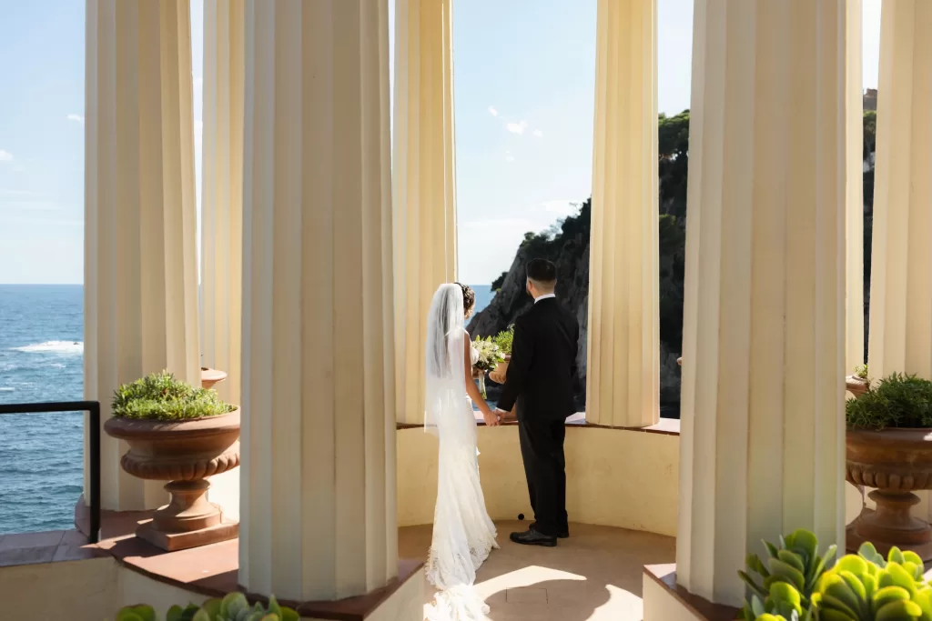 Couple holding hands and looking out at the cliffs and sea from the pavilion at Marimurtra Botanical Garden.