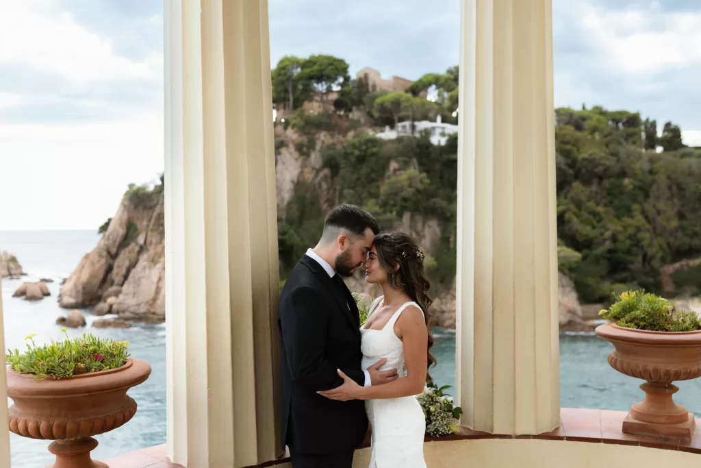 Bride and groom sharing an intimate moment between pavilion columns at Marimurtra Botanical Garden.