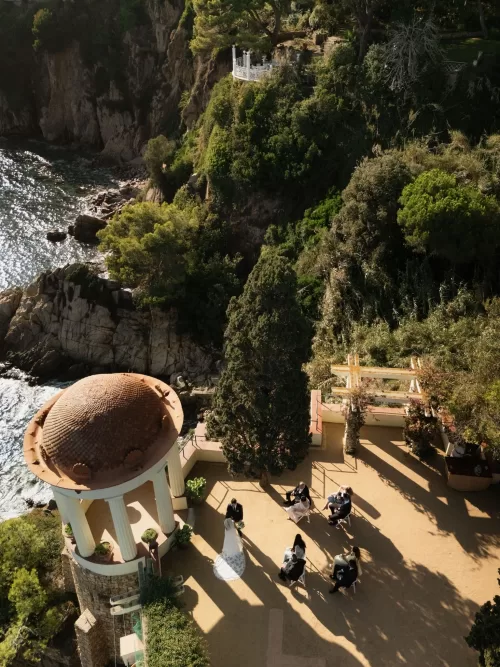 Cliffside pavilion ceremony at Marimurtra Botanical Garden with guests seated under the afternoon sun.