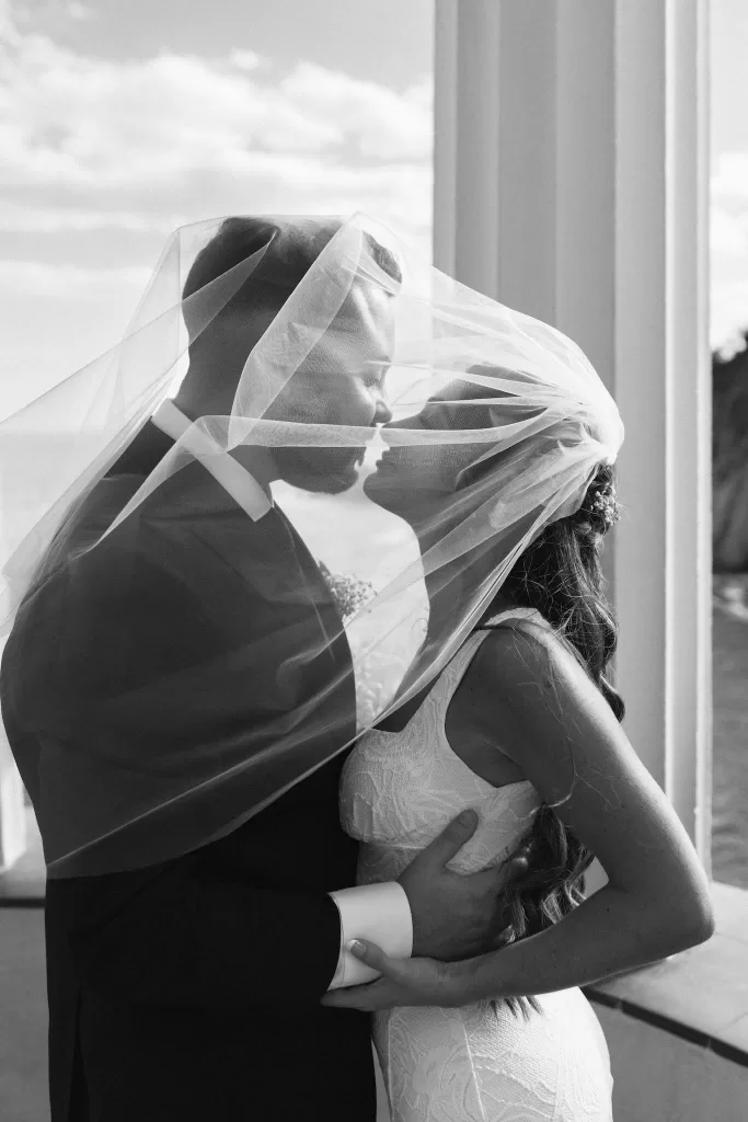 Romantic black and white photo of a bride and groom kissing under the bride’s veil at Marimurtra Botanical Garden.