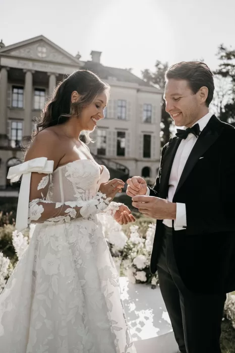 Bride and groom exchanging wedding rings in front of Parc Broekhuizen.