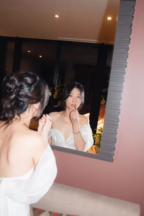 Bride applying lipstick in front of a mirror before the wedding at Six Senses Douro Valley.
