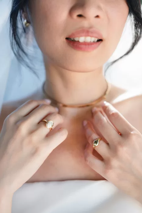 Close-up of bride’s hands adjusting necklace and rings before wedding at Six Senses Douro Valley.
