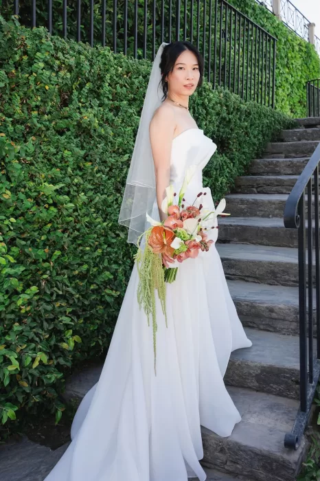 Bride in strapless gown holding bouquet on stone steps at Six Senses Douro Valley.