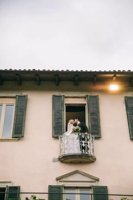 Newlyweds sharing a kiss on a charming balcony at Villa Bossi.