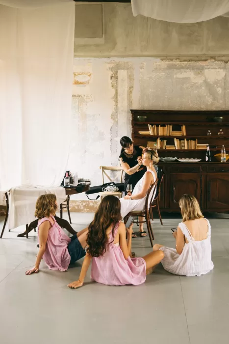 Bride getting her makeup done while bridesmaids relax during preparations at Villa Bossi.