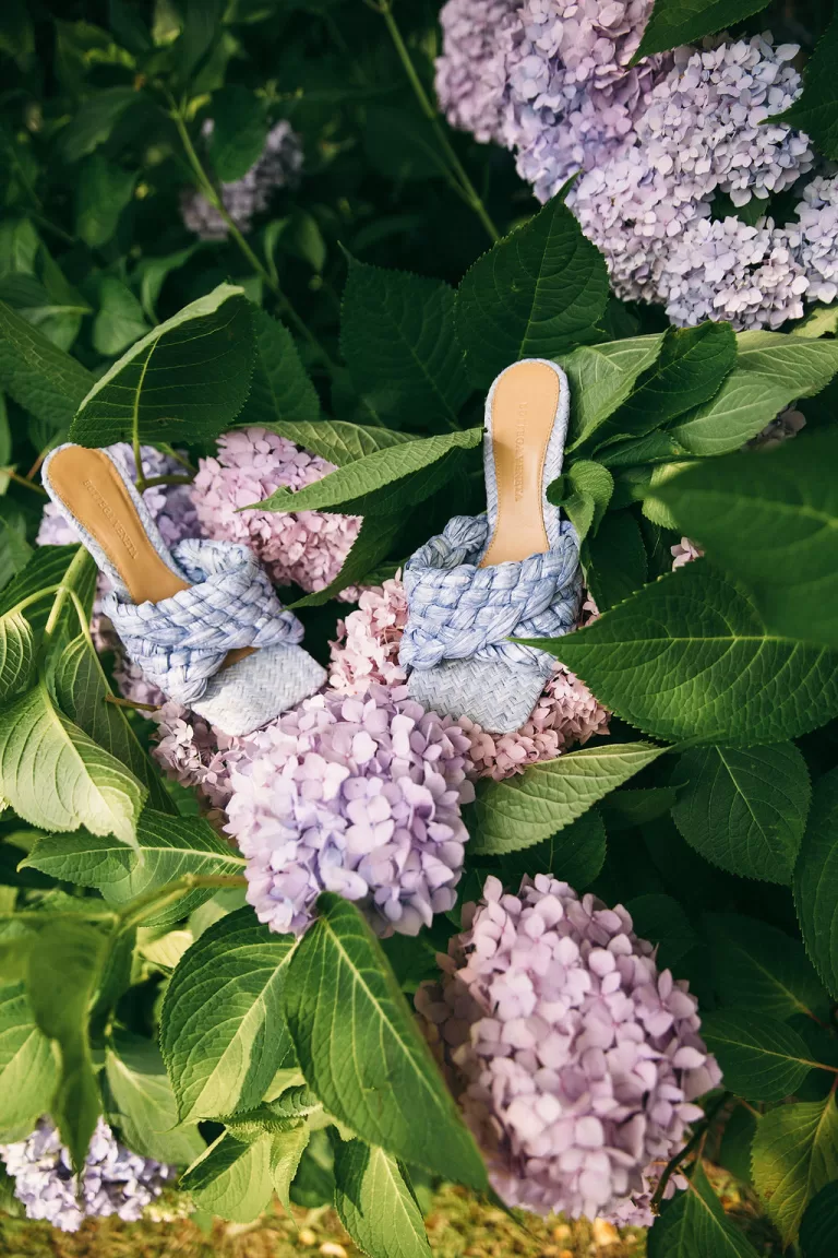 Light blue braided bridal shoes placed among blooming hydrangeas at Villa Bossi.