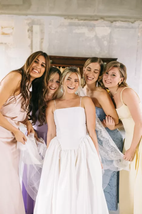 Bride surrounded by smiling bridesmaids in pastel dresses at Villa Bossi