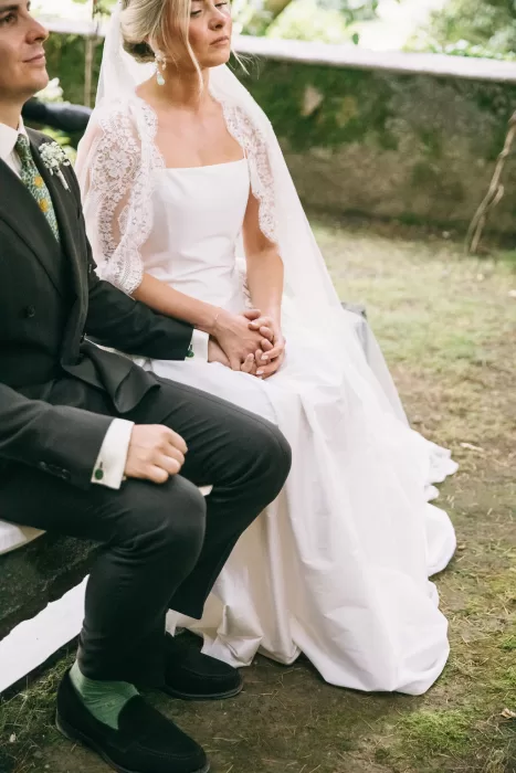 Bride and groom seated together holding hands during their wedding ceremony at Villa Bossi.