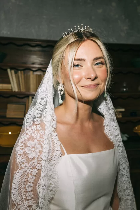 Bride in lace veil and tiara smiling softly during preparations at Villa Bossi.