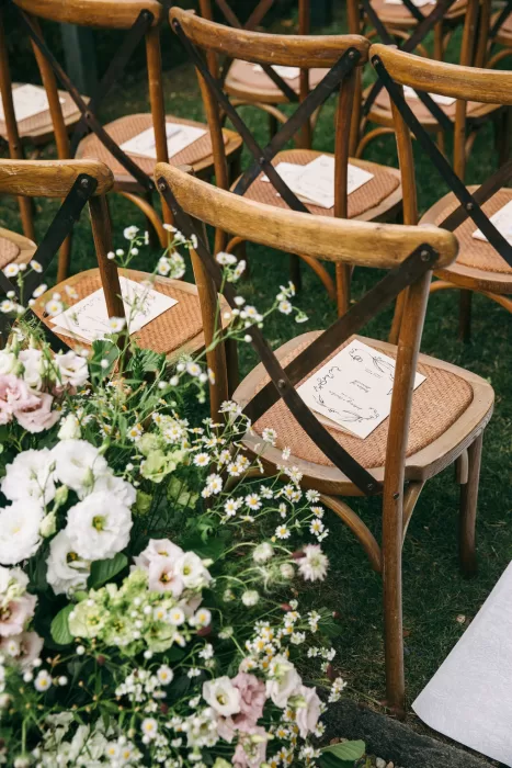 Ceremony seating decorated with rustic chairs, programs, and wildflowers at Villa Bossi.