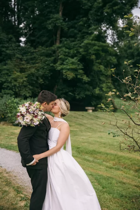Romantic kiss between bride and groom in the lush green gardens of Villa Bossi.