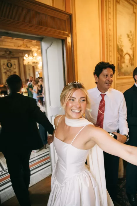 Bride joyfully entering the reception with guests in the ornate ballroom of Villa Bossi.