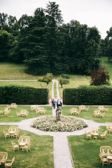 Guests walking through the manicured garden with a central statue at Villa Bossi.