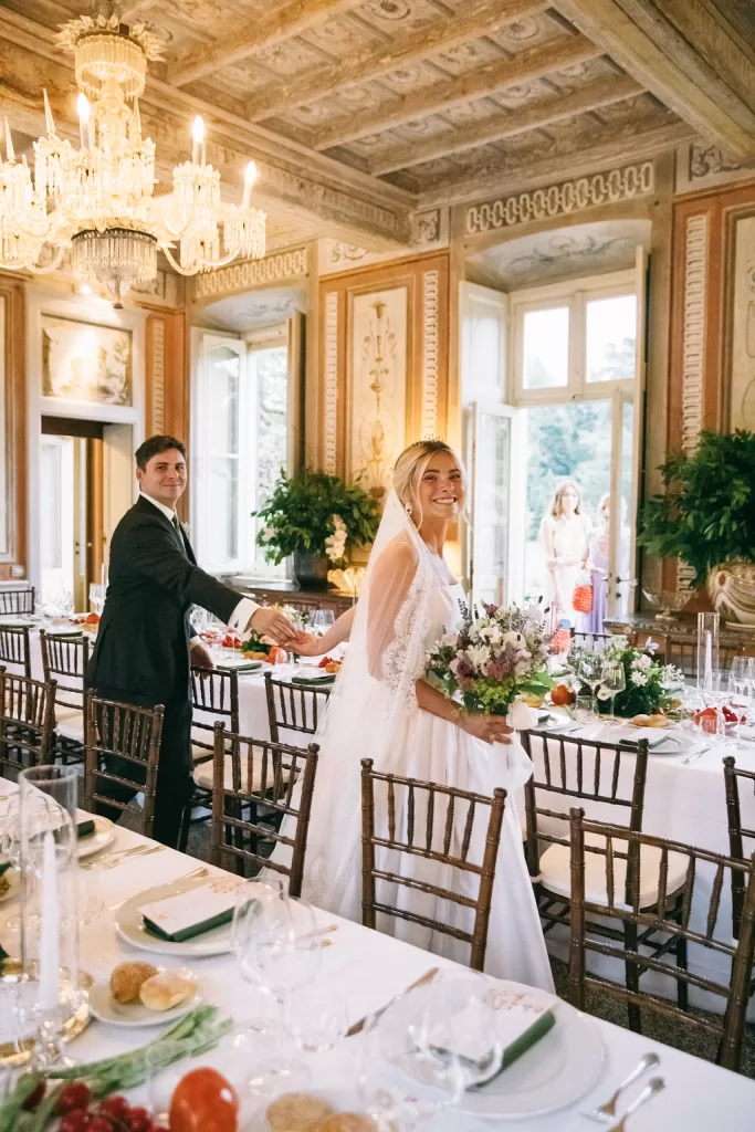 Bride and groom entering the grand chandelier-lit reception hall at Villa Bossi.