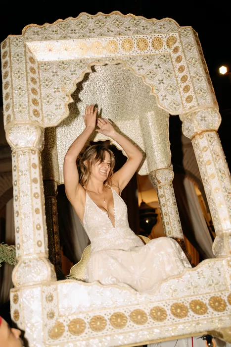 Bride smiling and raising her hands during the lively evening celebration at Beldi Country Club.