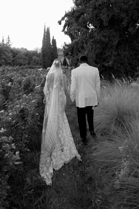 Bride and groom walking hand in hand through the rose garden at sunset at Beldi Country Club.