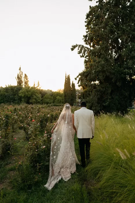Bride and groom walking hand in hand through the rose garden at sunset at Beldi Country Club.
