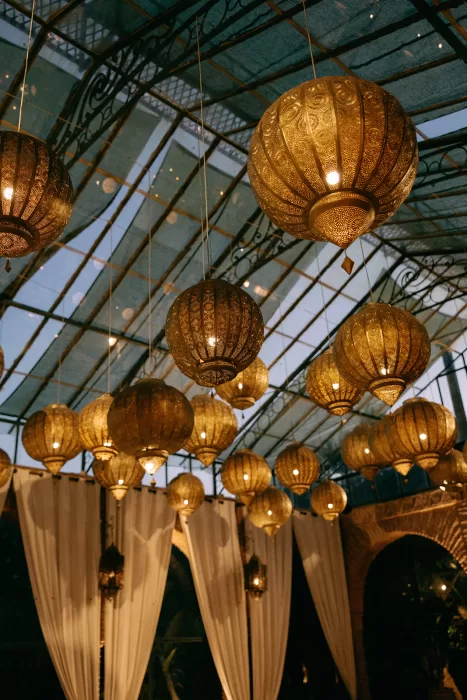 Ornate golden lanterns hanging from the glass ceiling at Beldi Country Club, casting a warm glow over the evening celebration.