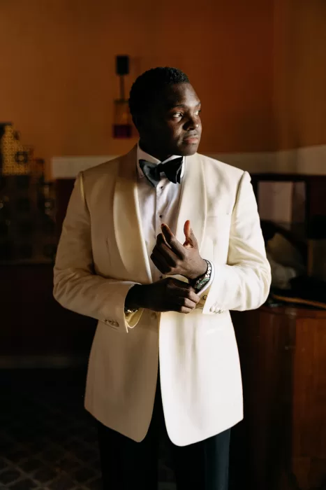 Groom adjusting his cufflinks in a softly lit room before the ceremony at Beldi Country Club.