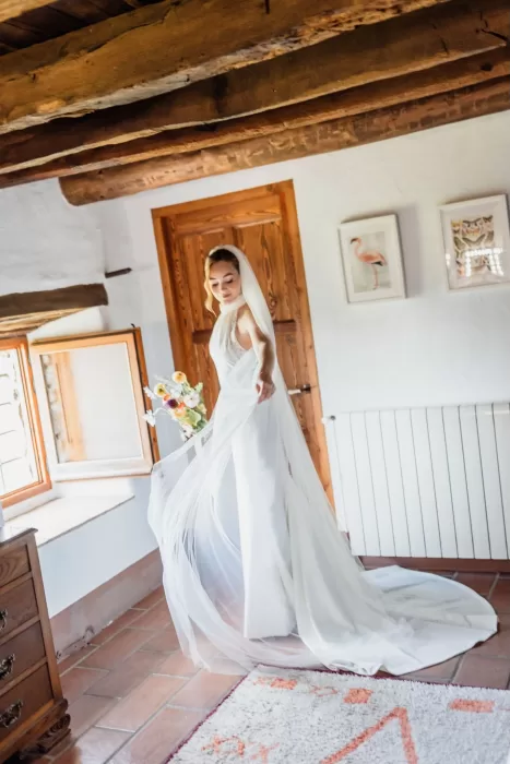 The bride twirls in her gown by an open window in the rustic dressing room at This Must Be The Place.