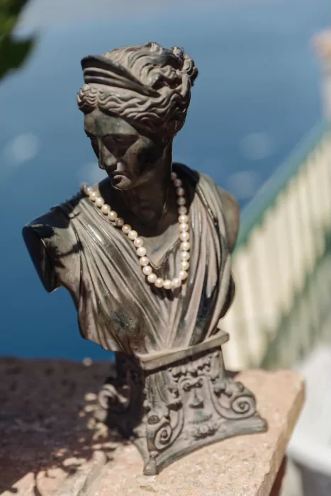 Bronze bust adorned with pearls at Caesar Augustus Capri, overlooking the blue Mediterranean Sea.