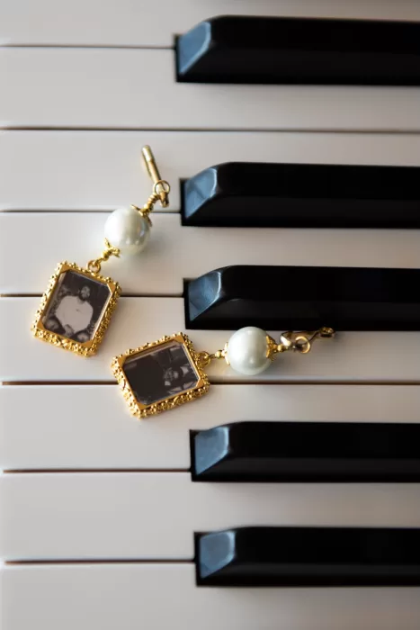 Gold and pearl heirloom earrings resting on piano keys, capturing elegant wedding details at Caesar Augustus Capri.