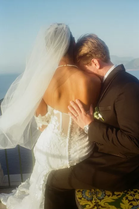 Groom holding bride close on the terrace of Caesar Augustus Capri, the sea glowing in soft evening light.