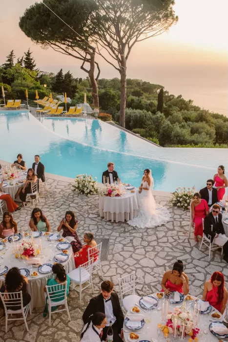 Outdoor wedding reception by the infinity pool at Caesar Augustus Capri during golden sunset light.