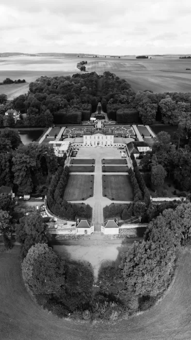 Aerial view of Château de Villette surrounded by manicured gardens and countryside fields in France.