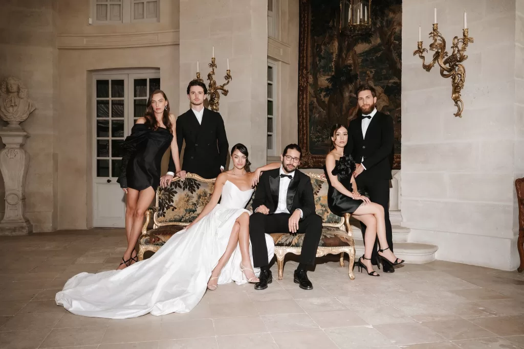 Bride and groom posing elegantly with their wedding party inside Château de Villette’s grand salon.