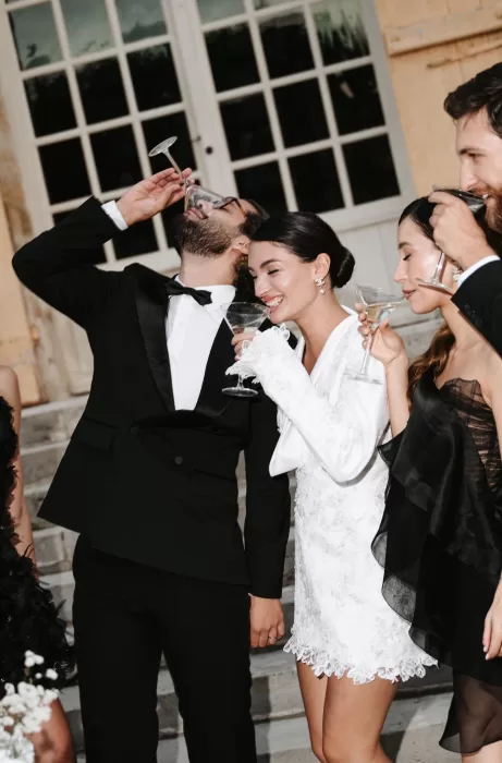 Bride and groom celebrating with friends and martinis on the steps of Château de Villette after the ceremony.