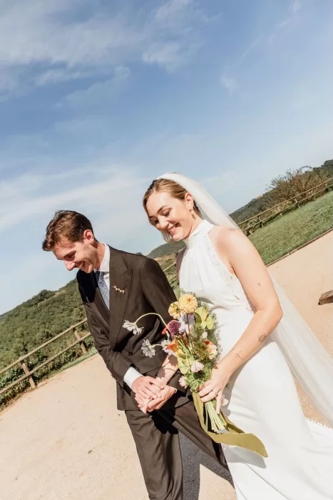 The couple smiling as they walk together outside This Must Be The Place, surrounded by scenic countryside views.