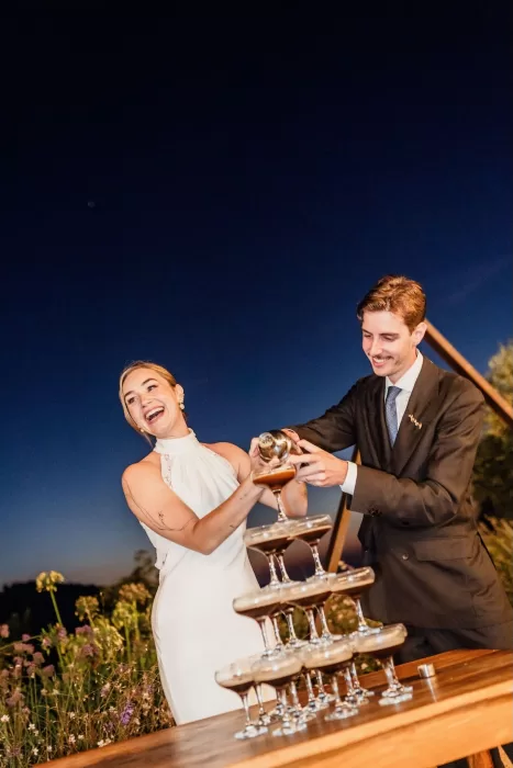 The couple joyfully pour espresso martinis into a glass tower during their evening celebration at This Must Be The Place.