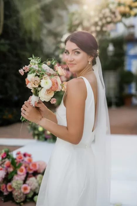 Bride smiles softly holding her pastel bouquet under the sunlight at Finca la Concepción.