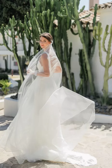Bride stands gracefully in the sunlight with her veil flowing around her at Finca la Concepción.
