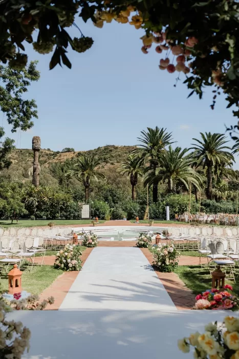 Outdoor wedding ceremony aisle lined with pastel flowers at Finca la Concepción, surrounded by palm trees and mountain views.