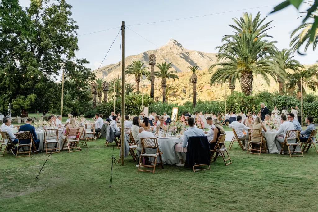 Guests dine under string lights surrounded by palm trees and mountains during the outdoor reception at Finca la Concepción.
