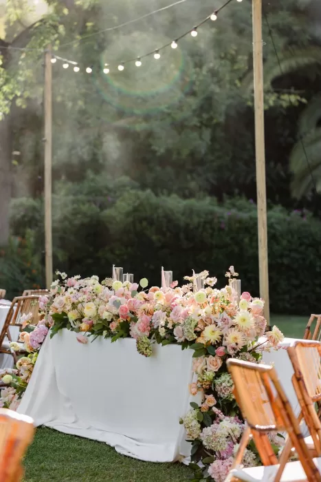 Romantic sweetheart table covered in soft pink and peach blooms under string lights at Finca la Concepción.