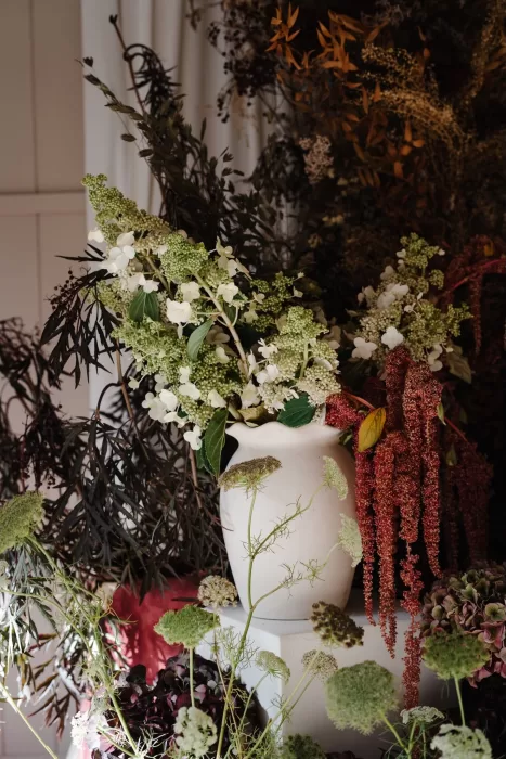 Textured floral arrangement at Hampton Manor featuring white hydrangeas, amaranthus, and greenery in a ceramic vase.