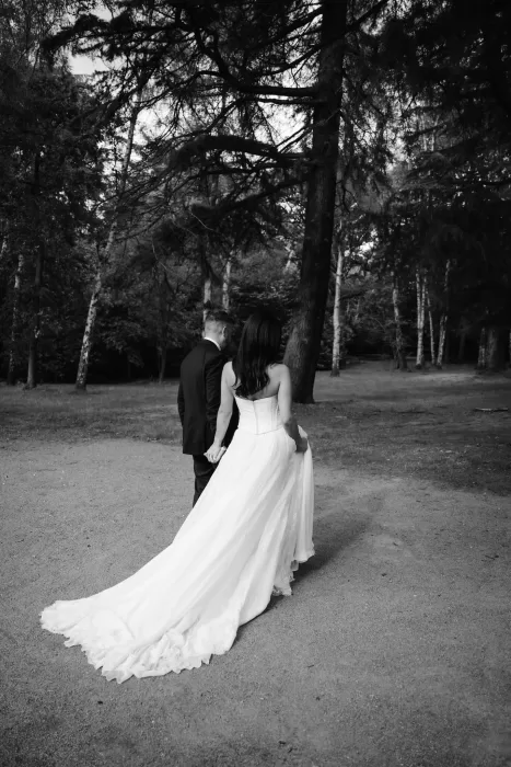 Bride and groom walking hand in hand through the woodland path at Hampton Manor.