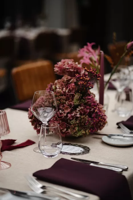 Mauve-toned floral centrepiece with hydrangeas and candles on a wedding table at Hampton Manor.