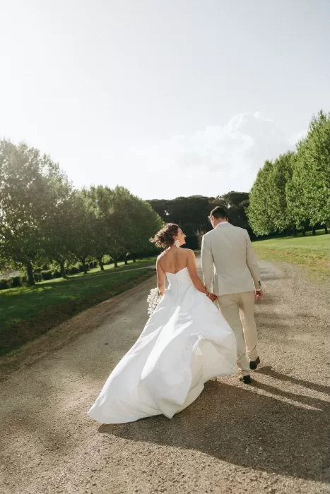 Bride and groom walking hand in hand down a sunlit lane at Herdade do Peru, radiating joy and romance.
