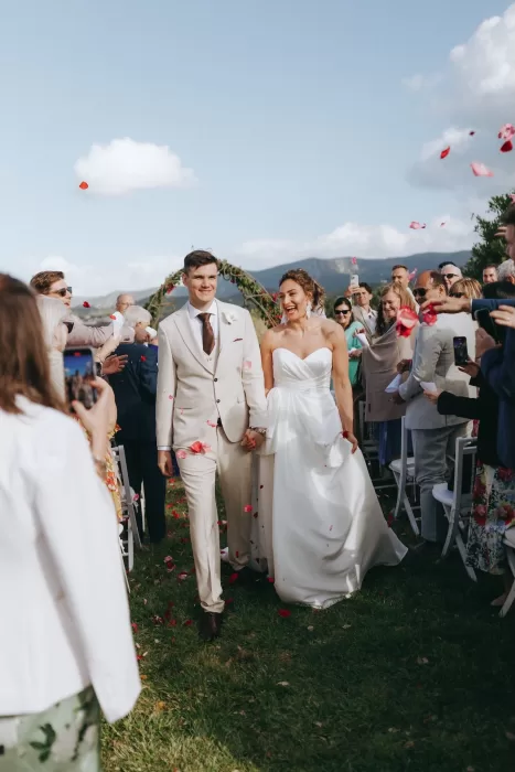 Bride and groom smiling as guests throw petals during their outdoor wedding ceremony at Herdade do Peru.