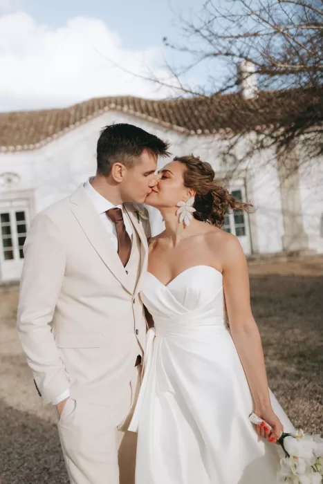 Newlyweds sharing a kiss in front of the villa at Herdade do Peru, bathed in soft afternoon light.