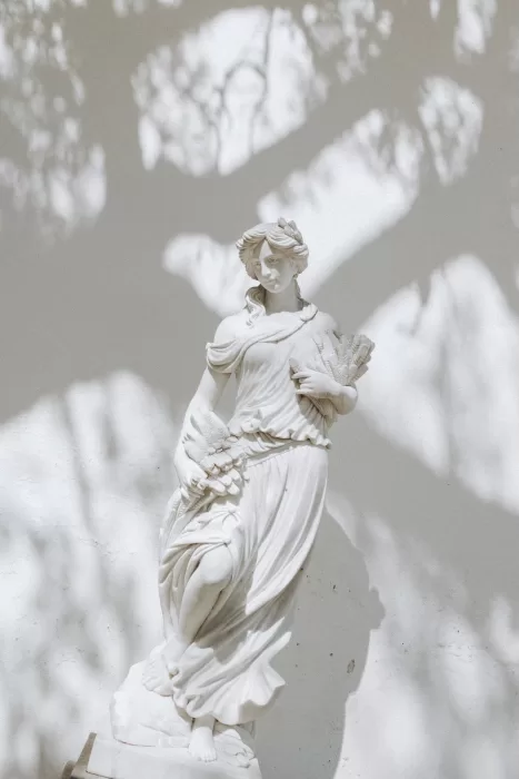 Marble statue surrounded by dappled light in the gardens of Herdade do Peru, evoking timeless classical beauty.