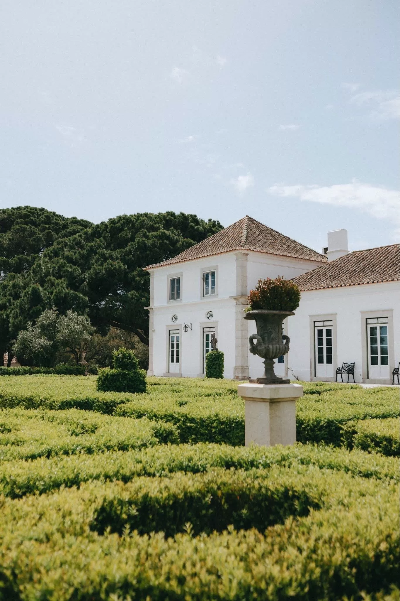 Elegant white manor overlooking manicured green hedges and scenic countryside at Herdade do Peru.