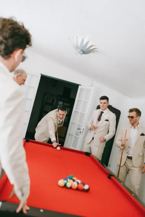 Groomsmen in cream suits playing pool at Herdade do Peru, enjoying relaxed pre-wedding moments.