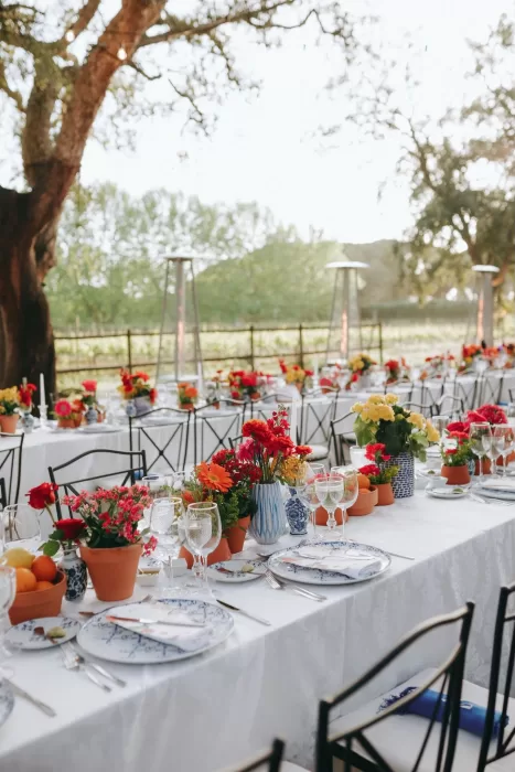 Outdoor wedding reception tables adorned with colorful flowers and blue patterned plates at Herdade do Peru.